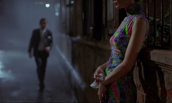 Movie still from “In the Mood for Love” (2000), directed by Kar-Wai Wong – A woman in a floral dress holding a nintendo wii game controller; Medium shot, Over the shoulder angle