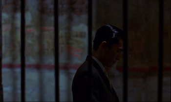Movie still from “In the Mood for Love” (2000), directed by Kar-Wai Wong – A man in a suit standing in front of a window; Medium shot, Low angle