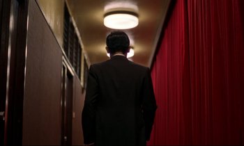 Movie still from “In the Mood for Love” (2000), directed by Kar-Wai Wong – A man in a suit walking down a hall way; Wide shot, Low angle