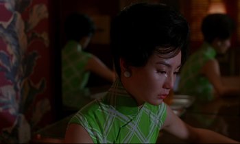 Movie still from “In the Mood for Love” (2000), directed by Kar-Wai Wong – A woman sitting at a table with her eyes closed; Close Up shot, High angle