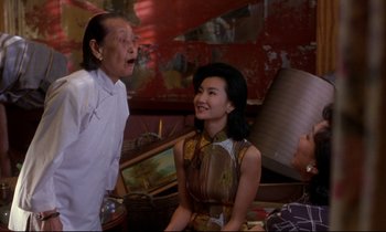Movie still from “In the Mood for Love” (2000), directed by Kar-Wai Wong – A man and a woman talking to another woman; Medium shot, Over the shoulder angle