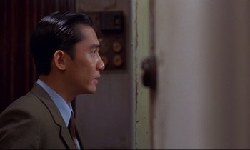 Movie still from “In the Mood for Love” (2000), directed by Kar-Wai Wong – A person wearing a suit and tie; Close Up shot, Over the shoulder angle