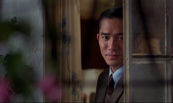 Movie still from “In the Mood for Love” (2000), directed by Kar-Wai Wong – A man wearing a suit and tie standing in front of a window; Close Up shot, Over the shoulder angle
