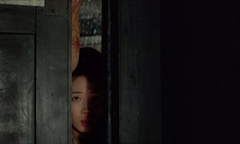 Movie still from “In the Realm of the Senses” (1976), directed by Nagisa Ôshima – A young girl peeking out from behind a wooden door; Close Up shot, Low angle