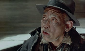 Movie still from “In the Realm of the Senses” (1976), directed by Nagisa Ôshima – An older man wearing a hat and a jacket; Close Up shot, Low angle