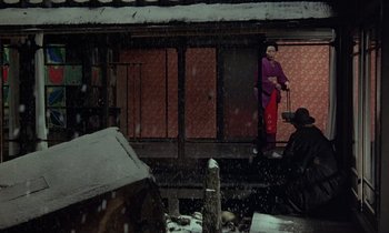 Movie still from “In the Realm of the Senses” (1976), directed by Nagisa Ôshima – A woman standing on the porch of a house in the snow; Extreme Wide shot, High angle