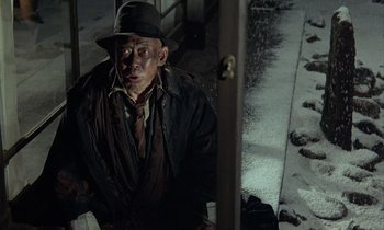 Movie still from “In the Realm of the Senses” (1976), directed by Nagisa Ôshima – A man wearing a hat and a jacket; Medium shot, Low angle