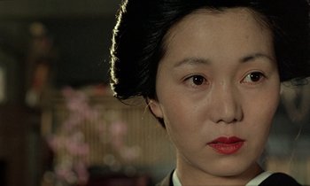 Movie still from “In the Realm of the Senses” (1976), directed by Nagisa Ôshima – A person wearing a suit and red lipstick; Close Up shot, Over the shoulder angle