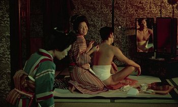 Movie still from “In the Realm of the Senses” (1976), directed by Nagisa Ôshima – A woman sitting on the ground with a man sitting on the floor; Medium shot, Over the shoulder angle
