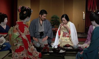 Movie still from “In the Realm of the Senses” (1976), directed by Nagisa Ôshima – Two geishas and a man in traditional japanese garb; Medium shot, High angle