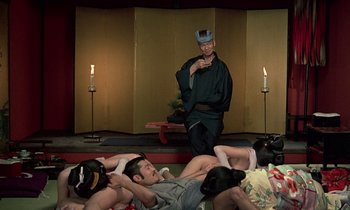 Movie still from “In the Realm of the Senses” (1976), directed by Nagisa Ôshima – A group of people laying on the ground and a man in a crown; Wide shot, High angle