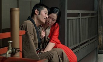 Movie still from “In the Realm of the Senses” (1976), directed by Nagisa Ôshima – A man and a woman sitting next to each other on a bench; Medium shot, High angle