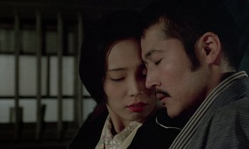 Movie still from “In the Realm of the Senses” (1976), directed by Nagisa Ôshima – A man and a woman snuggled up close to each other; Close Up shot, Low angle