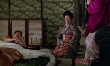 Movie still from “In the Realm of the Senses” (1976), directed by Nagisa Ôshima – An older woman sitting on the floor of a room; Medium shot, High angle