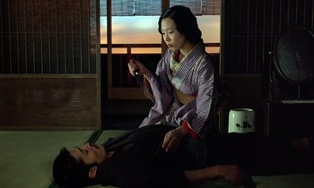Movie still from “In the Realm of the Senses” (1976), directed by Nagisa Ôshima – A man and a woman sitting on the ground; Medium shot, High angle