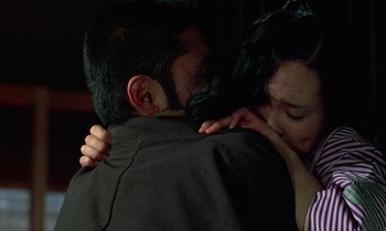 Movie still from “In the Realm of the Senses” (1976), directed by Nagisa Ôshima – A man and a woman hugging in a dark room; Close Up shot, Over the shoulder angle