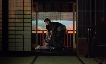 Movie still from “In the Realm of the Senses” (1976), directed by Nagisa Ôshima – A man kneeling down on the ground next to a woman; Wide shot, High angle