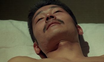 Movie still from “In the Realm of the Senses” (1976), directed by Nagisa Ôshima – A person laying on a bed; Close Up shot, High angle