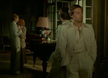 Movie still from “India Song” (1975), directed by Marguerite Duras – A group of people standing in a living room; Medium shot, Over the shoulder angle