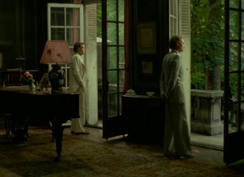 Movie still from “India Song” (1975), directed by Marguerite Duras – Two men standing in front of an open door; Wide shot, High angle