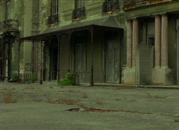 Movie still from “India Song” (1975), directed by Marguerite Duras – An old building with a lot of green plants growing on it; Extreme Wide shot, Low angle