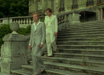 Movie still from “India Song” (1975), directed by Marguerite Duras – Two men walking up the steps of a building; Wide shot, Low angle