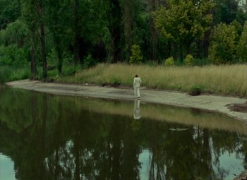 Movie still from “India Song” (1975), directed by Marguerite Duras – A man standing on the side of a body of water; Extreme Wide shot, High angle