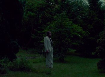 Movie still from “India Song” (1975), directed by Marguerite Duras – A man standing in the middle of a lush green field; Extreme Wide shot, Low angle