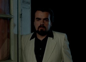 Movie still from “India Song” (1975), directed by Marguerite Duras – A man with a beard wearing a white jacket; Medium shot, Low angle