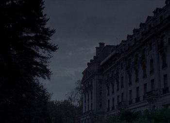 Movie still from “India Song” (1975), directed by Marguerite Duras – A building with a dark sky in the background; Extreme Wide shot, Low angle