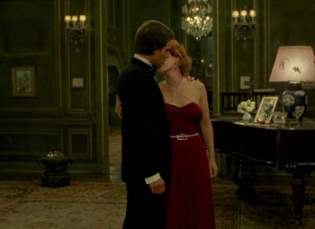 Movie still from “India Song” (1975), directed by Marguerite Duras – A man and a woman kissing in front of a grand piano; Wide shot, Low angle