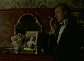 Movie still from “India Song” (1975), directed by Marguerite Duras – A man smoking a cigarette in front of a picture of a woman; Medium shot, Over the shoulder angle