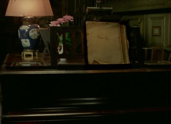 Movie still from “India Song” (1975), directed by Marguerite Duras – An old book sitting on top of a table next to a lamp; Extreme Close Up shot, High angle