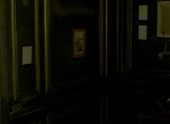 Movie still from “India Song” (1975), directed by Marguerite Duras – A dark room with a picture hanging on the wall; Medium shot, High angle