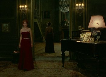 Movie still from “India Song” (1975), directed by Marguerite Duras – A woman in a red dress standing in front of a piano; Wide shot, High angle
