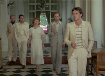 Movie still from “India Song” (1975), directed by Marguerite Duras – A group of men and women standing in front of a window; Wide shot, Low angle