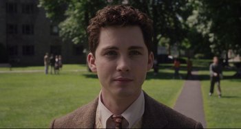 Movie still from “Indignation” (2016), directed by James Schamus – A man in a suit and tie in front of a grassy area; Close Up shot, Over the shoulder angle