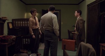 Movie still from “Indignation” (2016), directed by James Schamus – A group of men standing around in a room; Medium shot, Over the shoulder angle