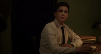 Movie still from “Indignation” (2016), directed by James Schamus – A man in a dress shirt and tie sitting in front of a wall; Medium shot, Over the shoulder angle