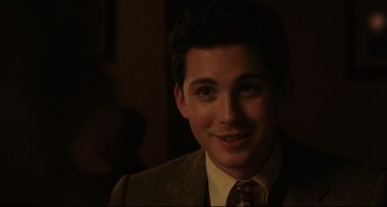 Movie still from “Indignation” (2016), directed by James Schamus – A man in a suit and tie smiling for the camera; Close Up shot, Over the shoulder angle