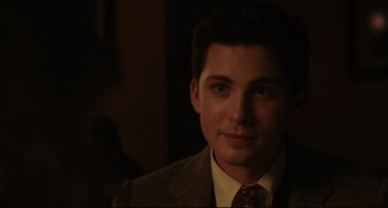 Movie still from “Indignation” (2016), directed by James Schamus – A man wearing a suit and tie in a dark room; Close Up shot, Over the shoulder angle