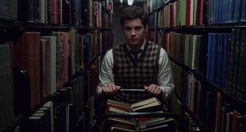 Movie still from “Indignation” (2016), directed by James Schamus – A man in a library with a bunch of books; Medium shot, High angle
