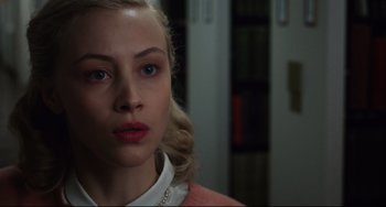 Movie still from “Indignation” (2016), directed by James Schamus – A woman with blonde hair wearing a white shirt and a pink jacket; Close Up shot, Over the shoulder angle