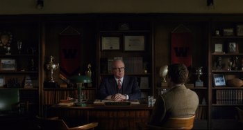 Movie still from “Indignation” (2016), directed by James Schamus – A man sitting at a desk in front of another man; Wide shot, Over the shoulder angle