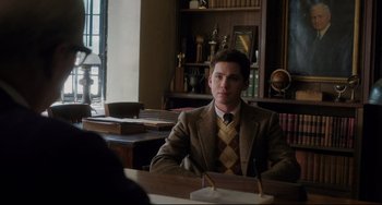 Movie still from “Indignation” (2016), directed by James Schamus – A man in a suit sitting at a table in a library; Medium shot, Over the shoulder angle
