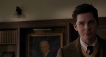 Movie still from “Indignation” (2016), directed by James Schamus – A man in a suit and tie standing in front of a painting; Close Up shot, Over the shoulder angle