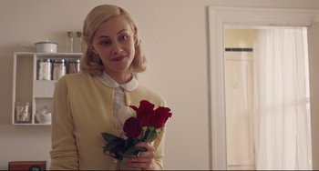 Movie still from “Indignation” (2016), directed by James Schamus – A woman holding a bouquet of roses in a room; Medium shot, Over the shoulder angle