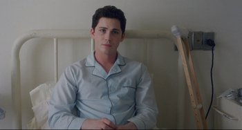 Movie still from “Indignation” (2016), directed by James Schamus – A young man in pajamas sitting on a couch; Medium shot, High angle