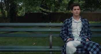 Movie still from “Indignation” (2016), directed by James Schamus – A man sitting on top of a green park bench; Medium shot, Over the shoulder angle