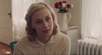 Movie still from “Indignation” (2016), directed by James Schamus – A woman sitting in front of a table with a vase of flowers; Close Up shot, Over the shoulder angle